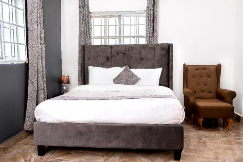 a bedroom with a large bed and a chair at Lovek Condos in Kumasi