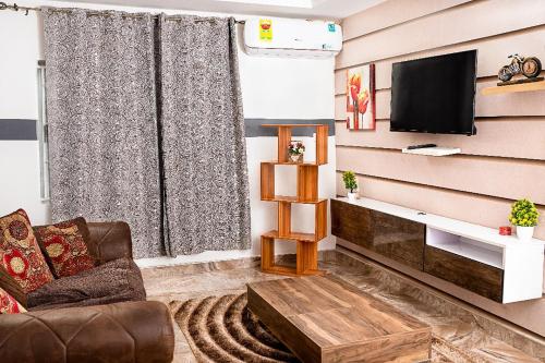 a living room with a couch and a tv at Lovek Condos in Kumasi