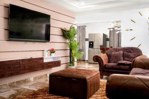 a living room with two chairs and a flat screen tv at Lovek Condos in Kumasi