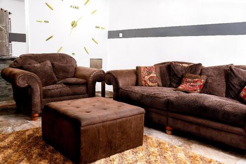 a living room with two couches and a clock on the wall at Lovek Condos in Kumasi