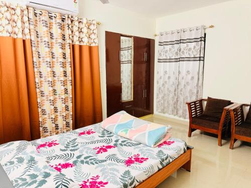 a bedroom with a bed and a chair and curtains at Lake View Garden in Trivandrum