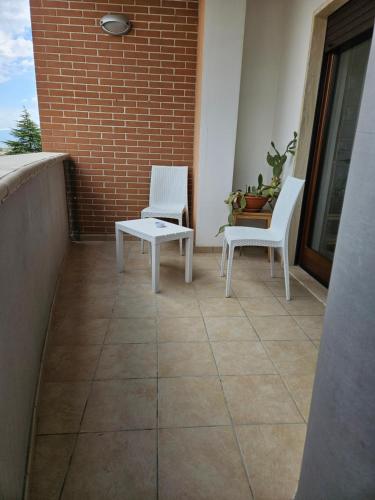 two white chairs and a table on a balcony at Residenza Montessori in Avezzano