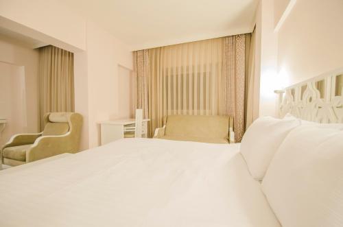 a bedroom with a large white bed and two chairs at Cimenoglu Hotel in Denizli