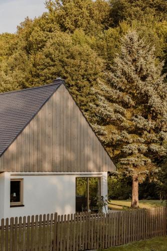 a barn with a fence next to a tree at Dom w Marczowie in Przezdziedza