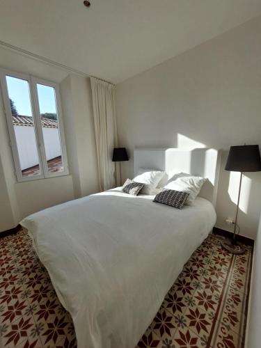 une chambre avec un grand lit blanc et deux fenêtres dans l'établissement La Suite 68 Bandol avec jardin et parking privatif, à Bandol