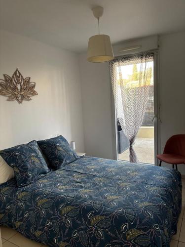 une chambre avec un lit avec une couverture bleue et une fenêtre dans l'établissement Apartment with private garage, à La Ciotat