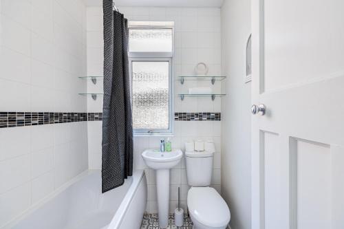 a white bathroom with a toilet and a sink at Charming Detached Bungalow - Close to Town Centre - Driveway Parking, Self-Check-In, Fast WiFi and Garden by Yoko Property in Northampton
