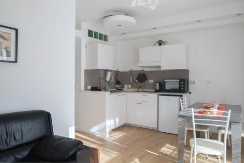 a kitchen with white cabinets and a table and a couch at L'Ulivo tourist accommodation in Bracciano