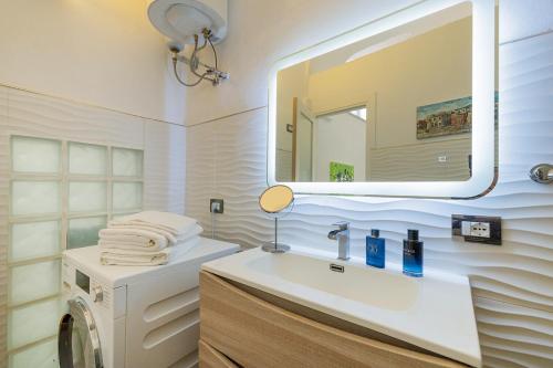 a bathroom with a sink and a mirror and a washing machine at The Beach One in Varigotti