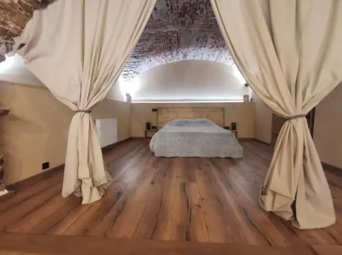 - une chambre dotée d'un lit avec des rideaux et du parquet dans l'établissement Appartement centre ville bastia, à Bastia