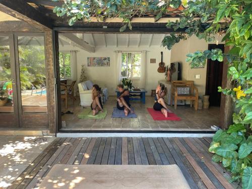 a group of three women sitting on yoga mats in a living room at Morada do Sol Guest House in Búzios