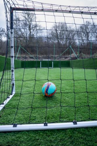a soccer ball sitting on a field next to a net at Kapcsolj ki Wellness Apartmanház Demjén in Demjén