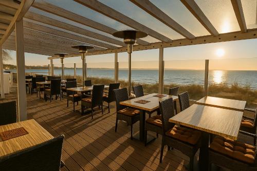a restaurant with tables and chairs and the ocean at Lodge am Meer in Glücksburg