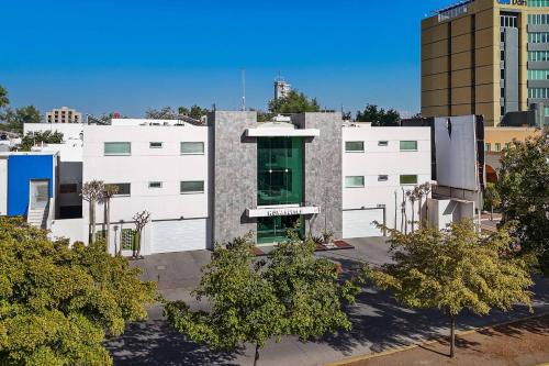 a white building with a green door in a city at Homesuites Zaragoza in Culiacán