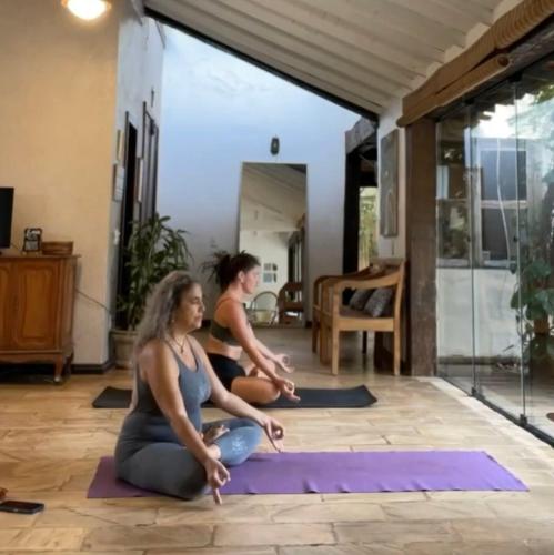 two women sitting in a yoga pose in a room at Morada do Sol Guest House in Búzios