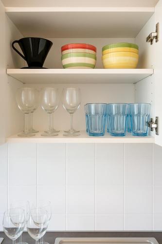 a shelf with bowls and wine glasses on it at Design Apartment mit Parkplatz - 15 min Flughafen in Offenbach