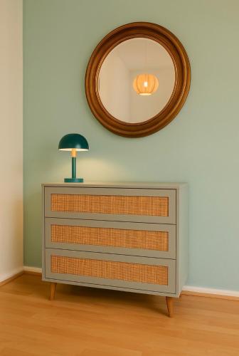 a dresser with a lamp and a mirror on the wall at Design Apartment mit Parkplatz - 15 min Flughafen in Offenbach