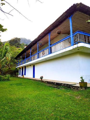 a building with a blue balcony and a green yard at Finca Rústica, Cocorná - Cacao, Charcos y Cascadas in Cocorná