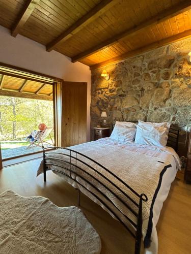 Un dormitorio con una cama con una pared de piedra. en Quinta do Espigueiro, en Celorico de Basto