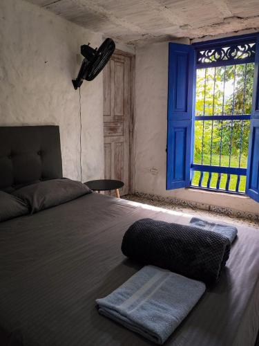 a bedroom with a bed with a blue window at Finca Rústica, Cocorná - Cacao, Charcos y Cascadas in Cocorná