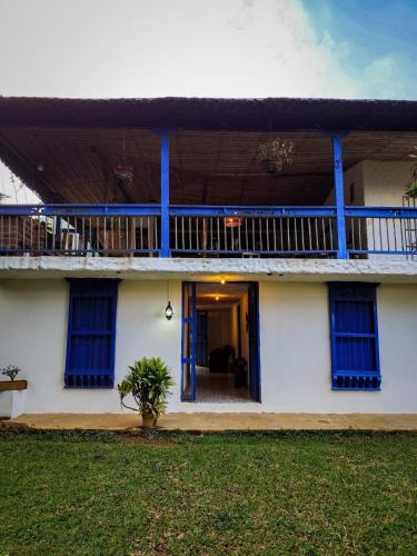a white house with blue windows and a balcony at Finca Rústica, Cocorná - Cacao, Charcos y Cascadas in Cocorná
