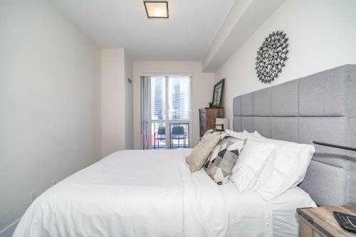a white bedroom with a large white bed with pillows at CHOL Furnished Suites Heart of Downtown Toronto, 2 Beds, Free Parking, CN Tower View in Toronto
