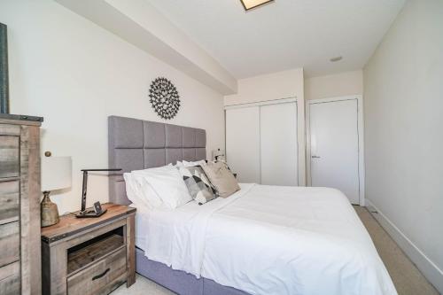 a bedroom with a white bed and a wooden night stand at CHOL Furnished Suites Heart of Downtown Toronto, 2 Beds, Free Parking, CN Tower View in Toronto