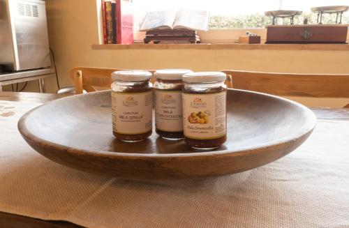 three jars of honey in a wooden bowl on a table at Il Poggio degli Antichi Sapori - Residence in Paternopoli