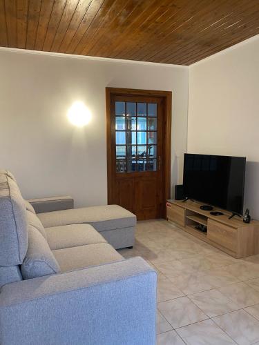 a living room with a couch and a flat screen tv at Paraíso Açoreano Guest House in Achada