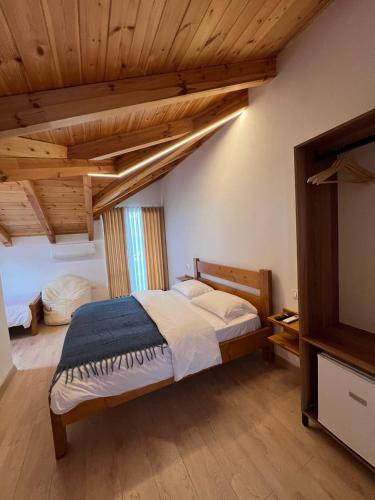 a bedroom with a large bed in a room with wooden ceilings at Tringa Guesthouse - Mrizi i Zanave in Fishtë