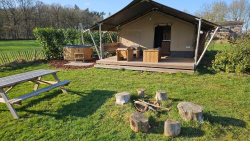 a tent with a picnic table and logs in the grass at Mooirust in Leersum
