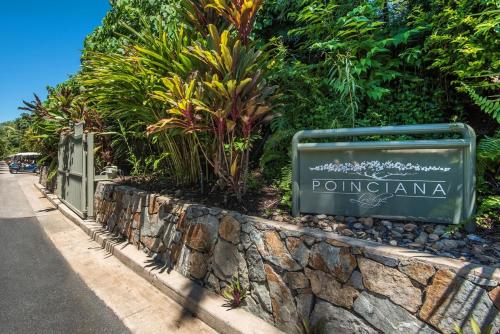 a sign on a stone wall next to a street at Poinciana 012 & Free Buggy Hamilton Island in Hamilton Island