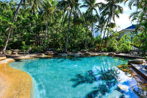 a swimming pool with palm trees in a resort at Poinciana 012 & Free Buggy Hamilton Island in Hamilton Island