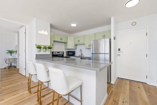 a kitchen with white cabinets and a counter with chairs at Waikiki Blue View in Honolulu