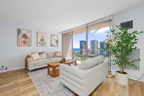 a living room with white furniture and a large window at Waikiki Blue View in Honolulu