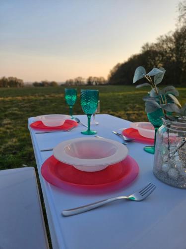 a table with a plate and wine glasses on it at Readers Field Glamping in Great Sampford