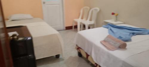 a room with two beds and two white chairs at Hostal La GRAN Familia in Manta