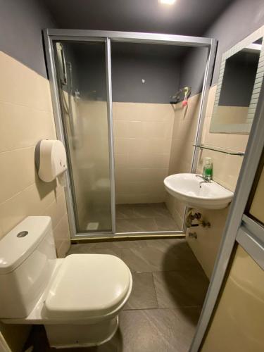 a bathroom with a shower and a toilet and a sink at Travelogue Guest House in Kuala Lumpur