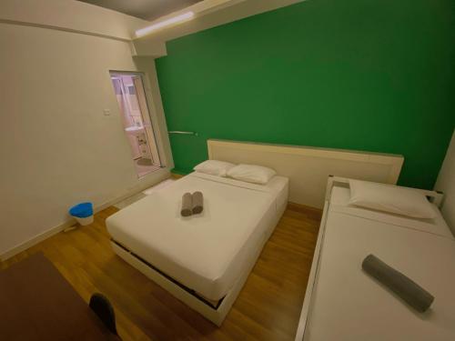 a room with two beds and a green wall at Travelogue Guest House in Kuala Lumpur