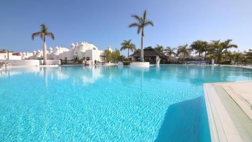 a large swimming pool with palm trees and buildings at Dúplex con vistas al mar in Playa Paraiso