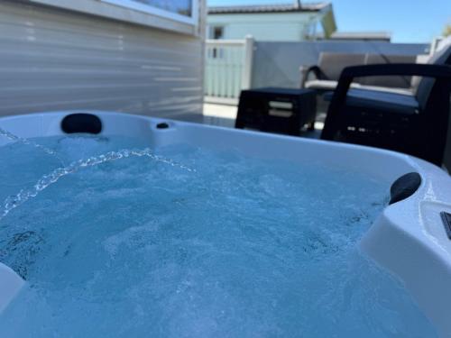 a hot tub filled with blue water in a yard at Fantasy Island Resort - The Pearl F10, with Hot Tub - Coastal Caravan Breaks in Ingoldmells