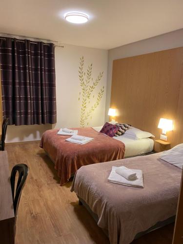 a hotel room with two beds with towels on them at Hôtel Le Saint Amand in Saint-Amand-Montrond