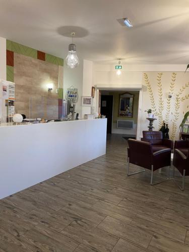 a lobby with a white counter and some chairs at Hôtel Le Saint Amand in Saint-Amand-Montrond