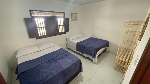 a room with two beds and a window at Casa do Arnaldinho in São Miguel dos Milagres