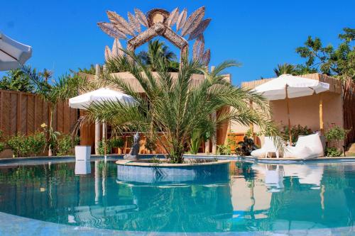 a resort swimming pool with a palm tree in the middle at VelaNova Paradise - HotelRetreat in Isla Fuerte