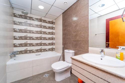 a bathroom with a toilet and a bath tub and a sink at Sunset Beach View Holiday Homes in Ajman 