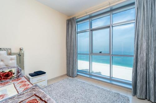 a bedroom with a large window with a view of the ocean at Sunset Beach View Holiday Homes in Ajman 