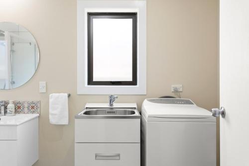 a white bathroom with a sink and a mirror at Central Family Home 5 min to CBD! in Gisborne