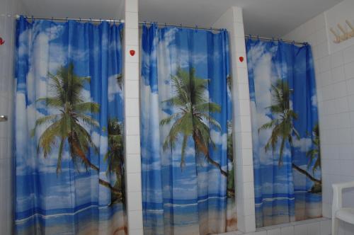 a bathroom with blue curtains with palm trees at Bélkő Panzió in Bélapátfalva