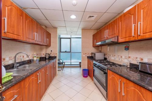a large kitchen with wooden cabinets and a sink at sand and beach haven at Ajman Corniche! in Dubai